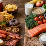 Ultra-realistic photograph comparing burgers, processed meats, fries, and sugary snacks with whole grains, vegetables, fruit, salmon, and dairy products.